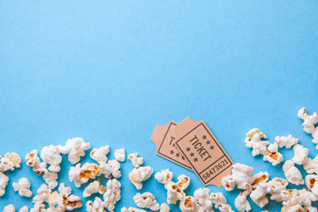 Movie tickets and popcorn on blue background. Copy space for text