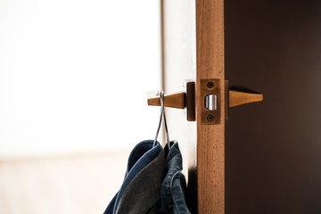 Obraz premium Ubrania na wieszaku wiszącym na klamce otwartych drzwi