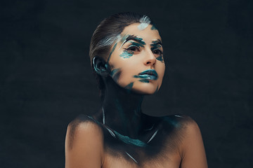 A young sensual girl with creative make-up. Blue and black shadows painted on her face. Conceptual idea.