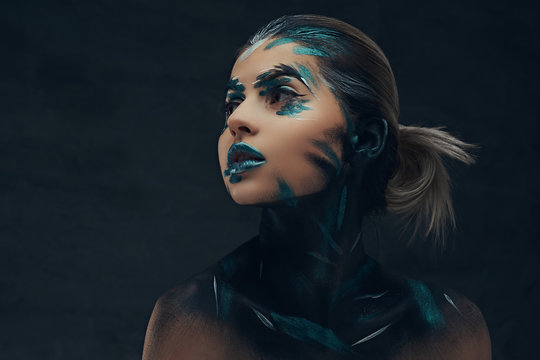 A young sensual girl with creative make-up. Blue and black shadows painted on her face. Conceptual idea.