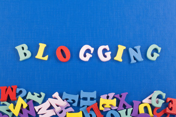 BLOGGING word on blue background composed from colorful abc alphabet block wooden letters, copy space for ad text. Learning english concept.
