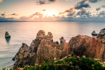 beautiful Atlantic ocean view horizon with sandy beach, rocks and waves at sunrise. Algarve,...