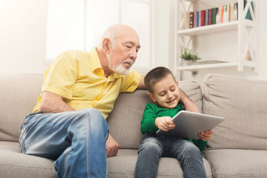 Senior man watching videos on tablet with grandson