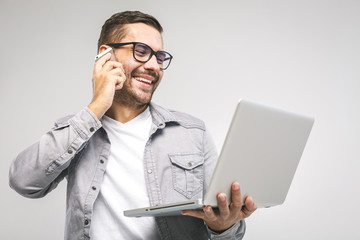 Happy excited smiling young man holding laptop and raising his arm up to celebrate success or achievement. White background. Using phone.