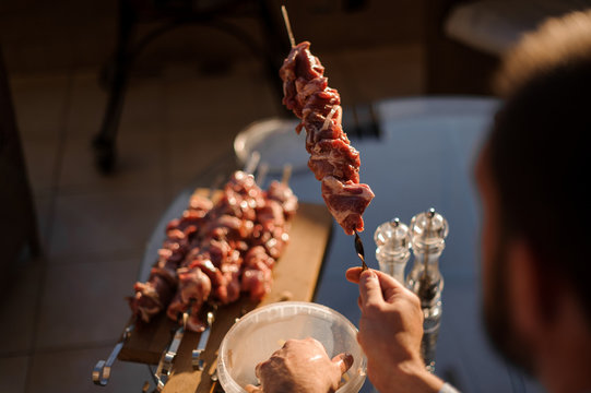 Rear view man holding in his hands a skewer with a fresh meat
