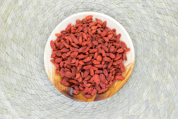 Heap of Dried Goji Berries Placed in Eco Natural Banana Leaf Plate on Bamboo Mat Background Surface with Free Space