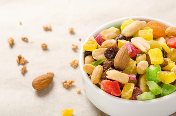 Mix of nuts and dried fruits - almonds, peanuts, raisins on white background in a bowl. Healthy food, snack