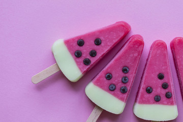 Watermelon shaped summer ice lolly on a pastel pink background