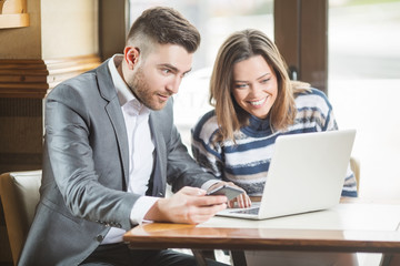 Business couple in cafe using laptop