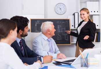 Fototapeta premium Manager female is reading financial report to colleagues on meeting