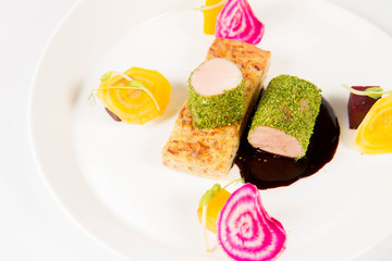 Roast pork tenderloin with crispy potato bread, marinated beetroots and green pepper sauce on a plate on a white background