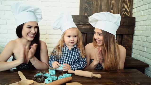 Lesbian Couple Cooking With Their Adopted Child. Sisters Cooking With Their Younger Brother.