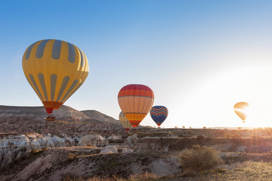 view of colorful hot air balloons flying over the Red valley on sunrise. Goreme, Cappadocia, Turkey.