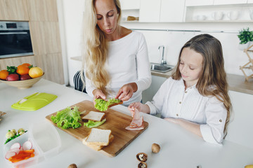 Mother daughter preparing school lunch home kitchen