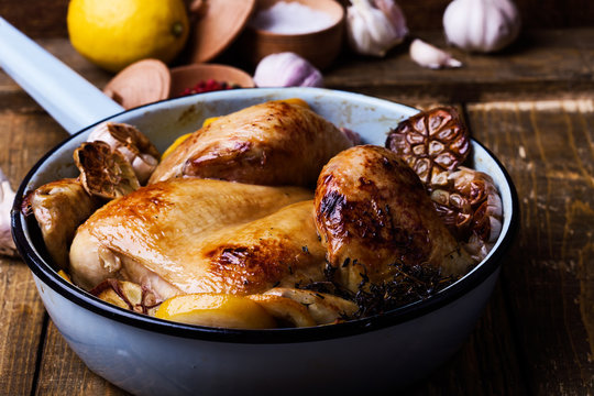 Roast chicken with garlic and lemon in cooking pan