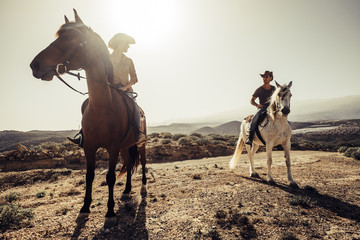 couple of horses and cowboys male and female ride free in the nature at the mountains in tenerife. lifestyle and alternative works or leisure activity concept for man and woman - obrazy, fototapety, plakaty