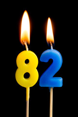 Burning candles in the form of 82 eighty two (numbers, dates) for cake isolated on black background. The concept of celebrating a birthday, anniversary, important date, holiday, table setting