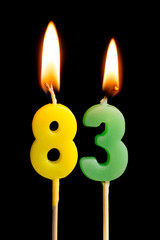 Burning candles in the form of 83 eighty three (numbers, dates) for cake isolated on black...