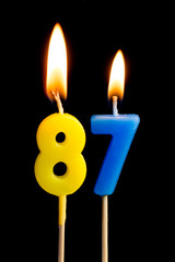 Burning candles in the form of 87 eighty seven (numbers, dates) for cake isolated on black...