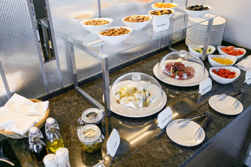 Breakfast in restaurant of hotel. Plates with food on a smorgasbord. Many plates in the background. Bar