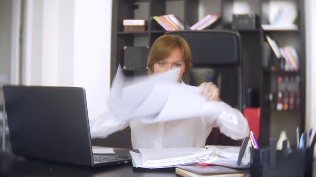 a businesswoman who scans documents, frowns, using a laptop, does not perform an urgent task in the office, there is not enough time, 4k