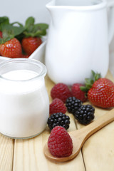 White yogurt with berries, blueberries, strawberries, raspberries, on  a wood table 