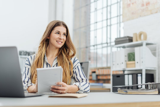Young smiling woman holding notepad in office