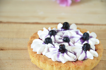 Berry mini tarts with the plate of berries over a white rustic wooden background, top view