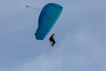 Parachutist with Blue Parachute against Clear Blue Sky