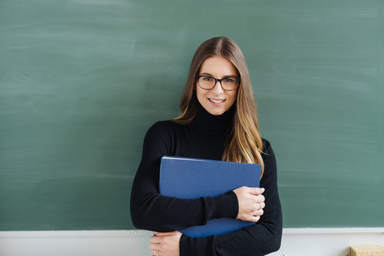 Young smiling female teacher against blackboard