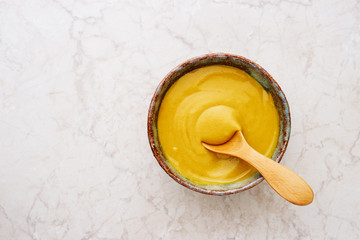 Fresh homemade English mustard sauce in bowl with wooden spoon top view - obrazy, fototapety, plakaty