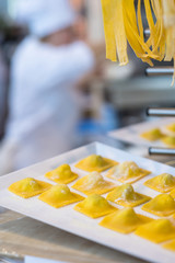 Making fresh ravioli and traditional pasta in a kitchen with cook in the background