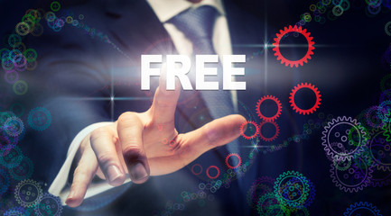 A businessman pressing a Free business concept on a graphical display of cogs