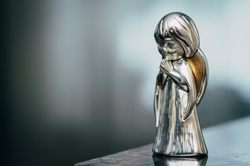 Small cute metall angel statue on blurred background