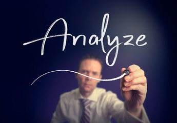 A businessman writing a Analyze concept with a white pen on a clear screen.