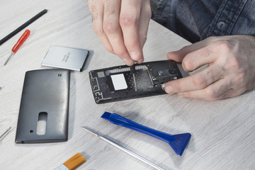 Dłonie pracownika serwisu telefonów odkręca śrubkę we wnętrzu telefonu komórkowego.