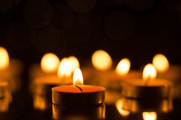 Candles in the dark with reflection and shallow depth of field, with lights in the background
