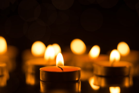 Candles in the dark with reflection and shallow depth of field, with lights in the background