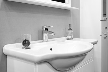 Luxury modern style faucet mixer on a white sink in a beautiful gray and white bathroom
