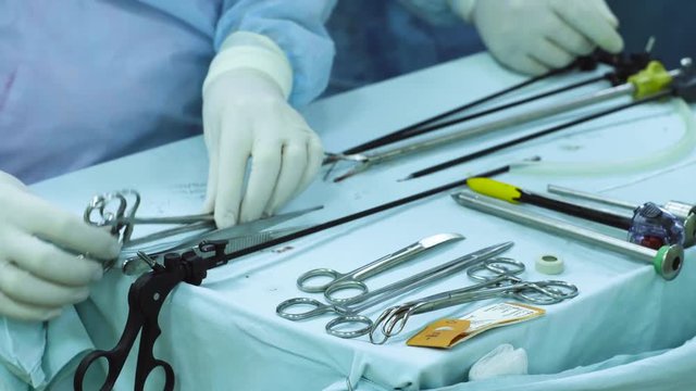 Close up hands and a table of surgical nurse during laparoscopic operation. Nurse preparing instrument