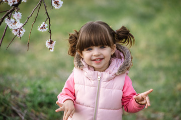 Pretty little girl in blossom apricot garden in beautiful spring day