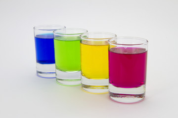 Multicolored glasses of different drinks. Party and holiday celebration concept. Four glasses with a blue, green, yellow and red drink. Isolated on white background.