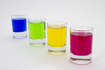 Multicolored glasses of different drinks. Party and holiday celebration concept. Four glasses with a blue, green, yellow and red drink. Isolated on white background.