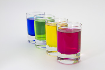 Multicolored glasses of different drinks. Party and holiday celebration concept. Four glasses with a blue, green, yellow and red drink. Isolated on white background.