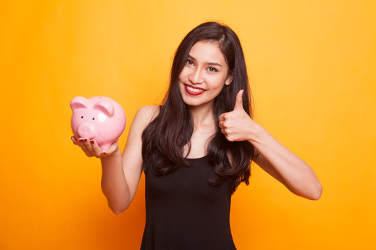 Asian woman show OK  with pig coin bank.