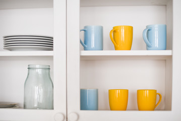 Fototapeta na wymiar Kitchen cupboard with colored cups