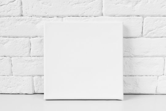 White primed canvas. Mockup poster. White brick wall on background.