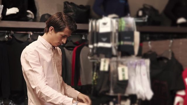 Close up shot of a stylish man going through different pair of socks indoor. He is taking a pair from the hanger.