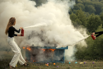 Firefighting of girl with extinguisher. Sexy woman with long hair at piano on fire, Halloween. Music style and art. Burning piano and fashion woman at rock concert. Fire and smoke on grunge instrument