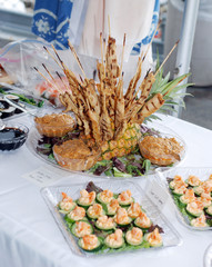 Chicken skewers, sushi appetizers sitting on a table at a wedding.